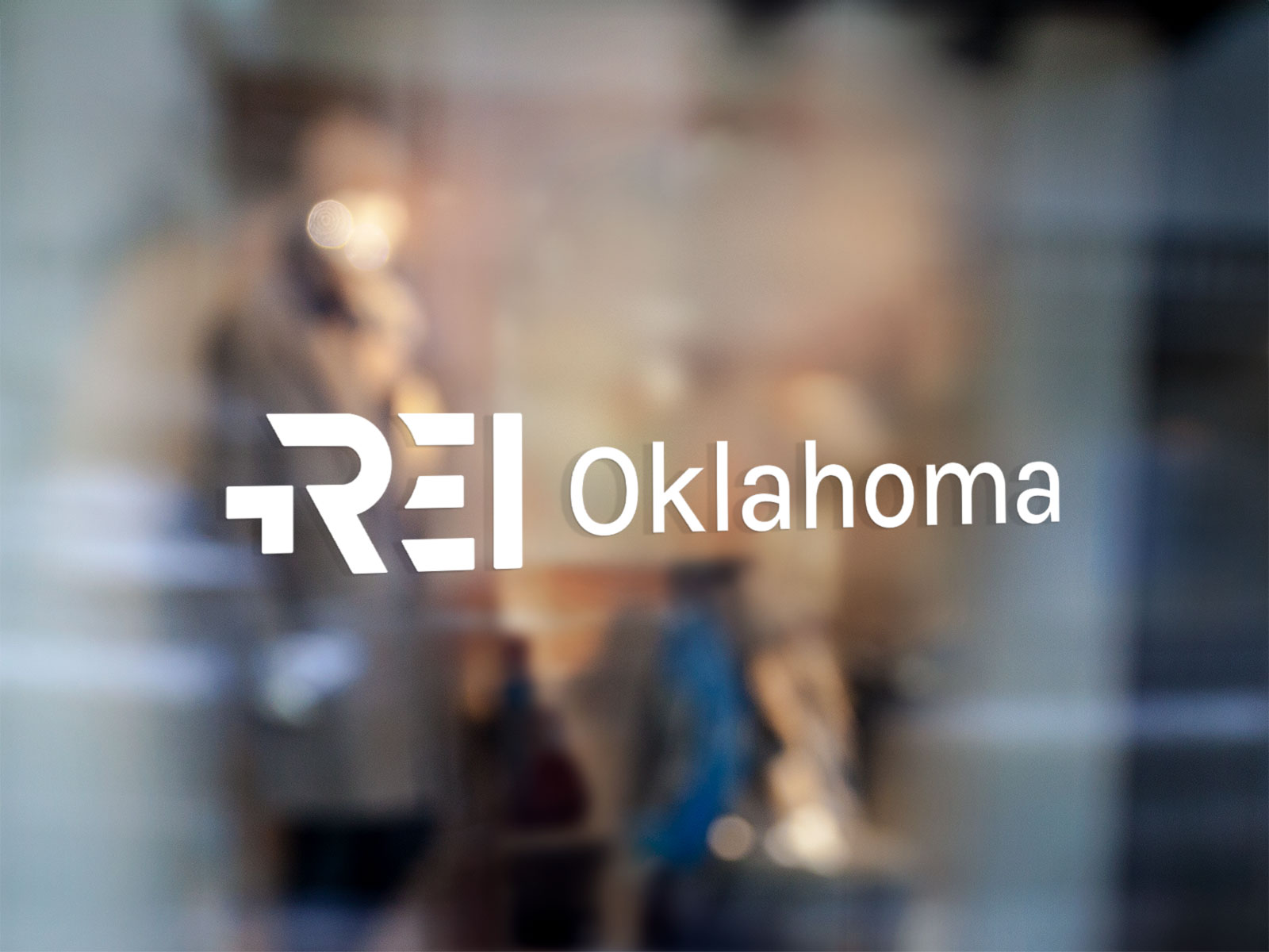 A mockup of REI Oklahoma brand identity collateral. A vinyl decal shows off the brand on the window of an REI Oklahoma fan business